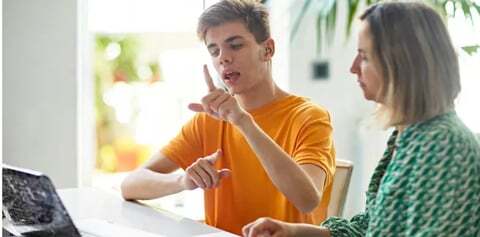 A young man speaks to a teacher with the help of a video BSL interprerer